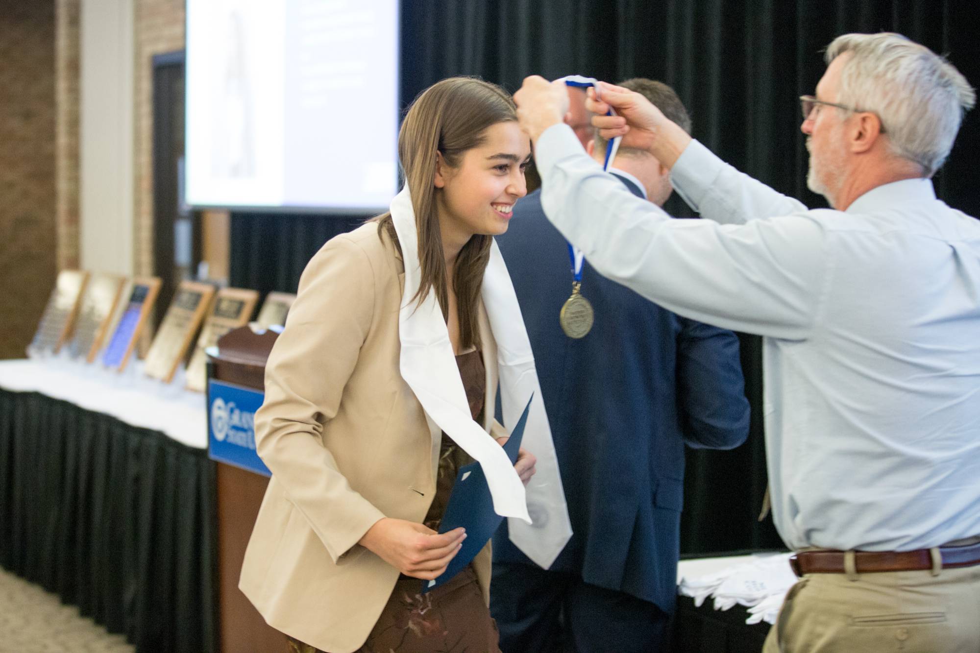 Honors graduate smiling while receiving their medallion